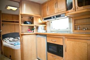 a kitchen with wooden cabinets and a microwave at Caravans Baško Polje in Baška Voda