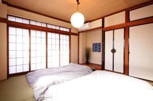 2 camas en una habitación con ventanas grandes en Guest House Re-worth Joshin1 3F, en Nagoya