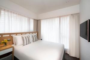 um quarto com uma cama branca e uma televisão em Shama Island North em Hong Kong
