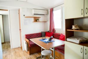 Habitación pequeña con mesa y sofá rojo. en Mobilhome Baška Voda | Kemp Baško Polje, en Baška Voda
