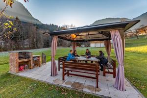 eine Gruppe von Menschen, die an einem Tisch unter einem Pavillon sitzen in der Unterkunft Haus Mühle in Sankt Gallenkirch