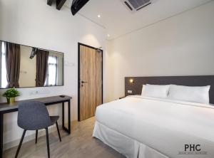 a bedroom with a bed and a desk and a chair at Macallum Central Hotel Managed by The Ascott Limited in George Town