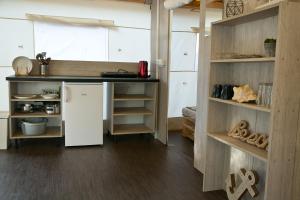 a kitchen with a white refrigerator and shelves at Glamping Tents - Camp Adriatic in Primošten