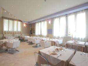a restaurant with white tables and chairs and windows at Hotel Souvenir in Monterosso al Mare