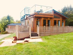 a small house with a deck and a fence at The Lodges at Sapey Golf & Country Club in Upper Sapey