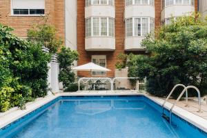 una piscina di fronte a un edificio di Hotel Gran Derby Suites, a Small Luxury Hotel of the World a Barcellona