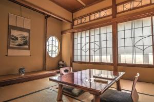 Habitación con mesa, sillas y ventanas. en K's House Ito Onsen - Historical Ryokan Hostel en Ito