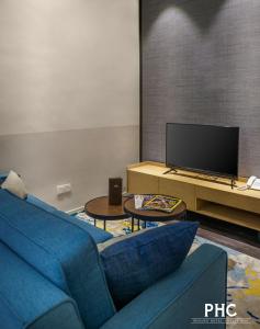 un salon avec un canapé bleu et une télévision dans l'établissement Bahari Parade Hotel by PHC, à George Town