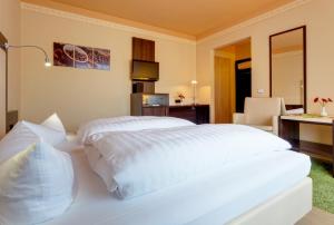 布賴騰布倫的住宿－阿爾特思飛瑞酒店，卧室配有一张白色大床、书桌和椅子
