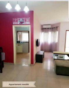 a living room with a couch and a red wall at Appart Sly Abidjan in Cocody