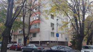 een wit gebouw met auto's ervoor geparkeerd bij Roza Apartment in Varna