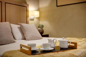 a tray with cups and tea sets on a bed at Intown Luxury House in Rome