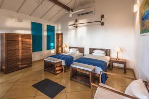 Habitación con 2 camas y sofá. en Kottukal Beach House by Jetwing, en Arugam Bay
