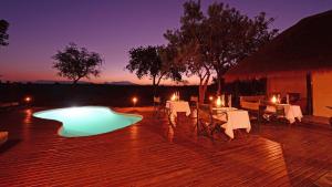 eine Terrasse mit einem Tisch, Stühlen und einem Pool in der Unterkunft Tangala Safari Camp in Thornybush Game Reserve