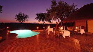 a deck with a table and chairs and a pool at Tangala Safari Camp in Thornybush Game Reserve