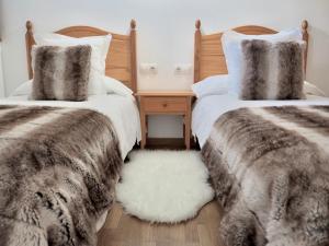 two beds with faux fur pillows and a white rug at Vora Riu in Esterri d'Àneu