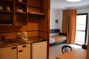 a kitchen with a sink and a room with a bed at Apartaments Rosanna in Lloret de Mar