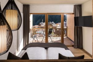 1 Schlafzimmer mit einem Bett und einem Balkon mit einem Tisch in der Unterkunft Falkensteiner Hotel & Spa Falkensteinerhof in Vals