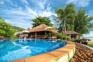 a beach with a pool, chairs, and a pool table at Thiwson Beach Resort - SHA Extra Plus in Ko Yao Yai