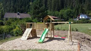 a wooden playground with a slide in a yard at Hotel Panorama in Elbigenalp