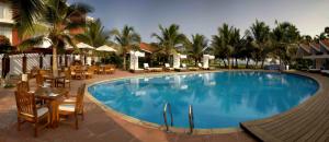 a large swimming pool with tables and chairs and palm trees at The Park Visakhapatnam in Visakhapatnam