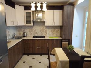 a kitchen with white cabinets and a table and a dining room at Euro Mini-Hotel in Mazyr
