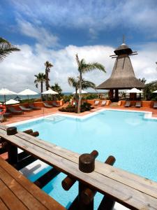 a swimming pool with a wooden bench in a resort at Royal Hideaway Sancti Petri in Chiclana de la Frontera