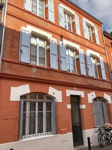 ein rotes Backsteingebäude mit weißen Fensterläden darauf in der Unterkunft Appartements Dom Vaissette in Toulouse