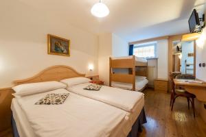 una camera d'albergo con letto, scrivania di Hotel Al Lago a Soraga