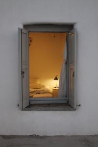 a window in a white wall with a bed in a room at Alitanes in Áno Meriá