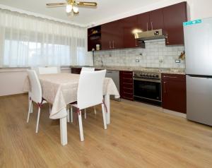 a kitchen with a table and white chairs and a refrigerator at Casa Nonna Elvira in Roccalumera