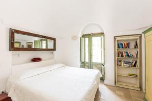 ein weißes Schlafzimmer mit einem Bett und einem Spiegel in der Unterkunft Trulli Masseria Donno Santo in Ceglie Messapica