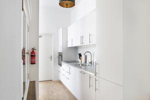 uma cozinha com armários brancos e um lavatório em SC 1 Cozy Family & Business Flair welcomes you - Rockchair Apartments em Berlim