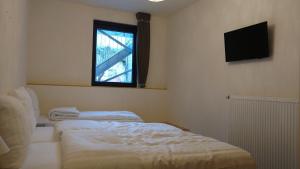 a bedroom with two beds and a television on the wall at Hotel Ladeuze in Leuven