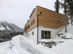 a building on a snow covered road with a building at Appartement am Berg in Ebene Reichenau