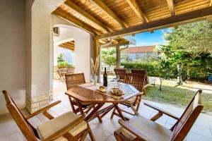 a patio with a wooden table and chairs on it at Villas Rab Banjol in Rab