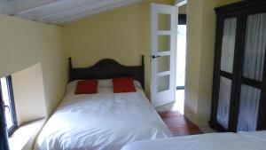 a bedroom with a bed with two red pillows on it at Finca El Zurrador in Fuenteheridos