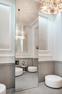 a bathroom with two mirrors and a chandelier at Hospes Puerta de Alcalá in Madrid