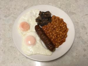 a plate of food with eggs beans and sausage at Hawthorn House Hotel in Kettering