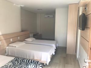 a hotel room with two beds and a television at Suíte Hotel Vitória in Vitória