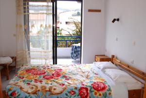 a bedroom with a bed with a floral comforter at Rosmari Hotel in Archangelos