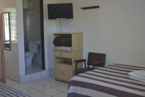 a bedroom with a bed and a television and a mirror at Hotel Nelly in São Gabriel