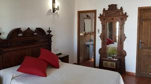 a bedroom with a bed with red pillows and a mirror at Hotel Rural La Casa de los Tres Cielos in Campo de Criptana