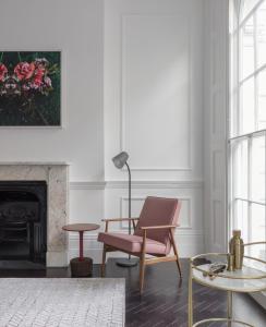 a living room with a pink chair and a fireplace at The Moorgate by COVE in London