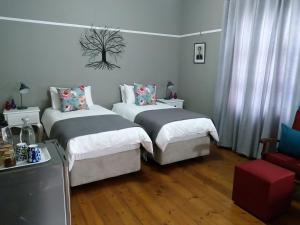 a hotel room with two beds and a tv at Casa Mia in Pietermaritzburg