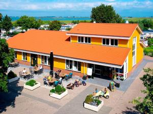 un edificio de techo naranja con gente sentada fuera de él en Friesland-cottage, en Molkwerum