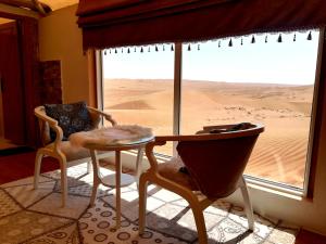 Habitación con mesa y sillas frente a una ventana en Safari Dunes Camp, en Ḩawīyah
