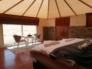 a bedroom with a bed and a table with chairs at Safari Dunes Camp in Ḩawīyah