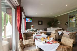 a dining room with tables and chairs and a couch at Les Jardins d'Ulysse, The Originals Relais Le Touquet in Stella-Plage