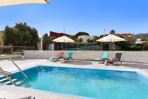 a swimming pool with chairs and umbrellas at Los Algodones Cottage with Pool in Ingenio